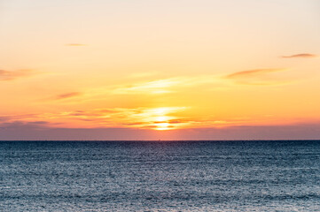 オレンジ色に朝焼けする空と海