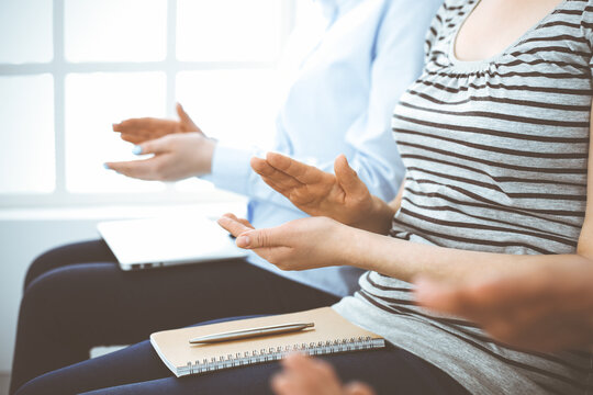 Business people clapping at meeting or conference, close-up of hands. Group of unknown businessmen and women in modern white office. Success teamwork, corporate coaching and applause concept