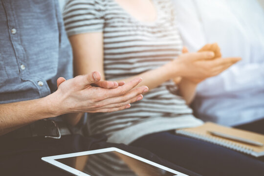 Business people clapping at meeting or conference, close-up of hands. Group of unknown businessmen and women in sunny office