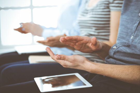 Business people clapping at meeting or conference, close-up of hands. Group of unknown businessmen and women in modern white office. Success teamwork, corporate coaching and applause concept