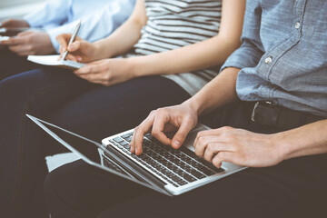 Group of casual dressed business people working at meeting or conference, close-up of hands. Businessman using laptop computer. Teamwork or coaching concept