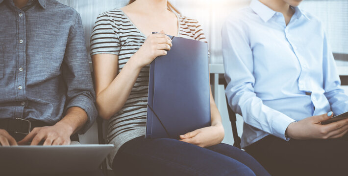 Group of casual dressed business people sitting in a line while waiting for a job interview in sunny office