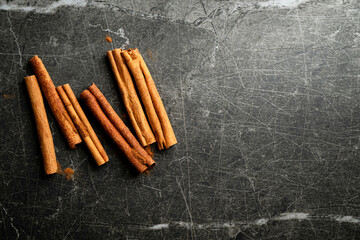 Overhead view of cinnamon sticks on a black and gray marbled background with copy space.