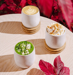 Colorful coffee drinks on a wooden table with autumn leaves