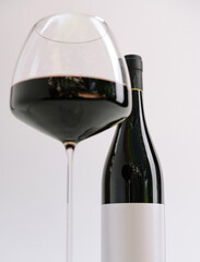 Elegant red wine glass beside a bottle in minimalist setting