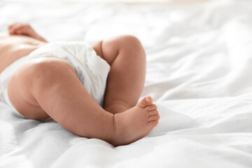 Cute little baby in diaper on bed, closeup