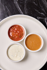 A decorative plate holds three enticing dipping sauces, each unique in flavor and color