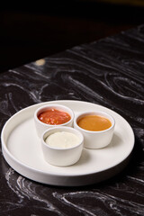 A decorative plate holds three enticing dipping sauces, each unique in flavor and color