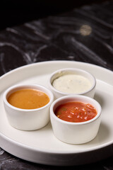 A decorative plate holds three enticing dipping sauces, each unique in flavor and color