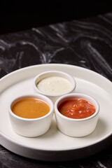 A decorative plate holds three enticing dipping sauces, each unique in flavor and color