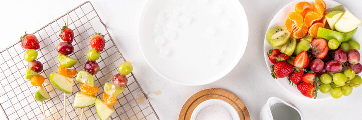 Traditional Chinese sweet street food recipe Tanghulu, fruit skewer on stick with crunchy sugar glaze, easy healthy dessert. Step by step preparation of Tanghulu with ingredients on table, top view