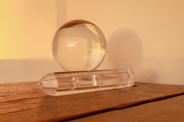 Clear crystal ball sphere resting atop a quartz  crystal point on a wooden surface