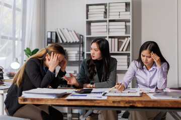 Stressed annoyed office employee manager having headache migraine at business meeting with colleagues about business problem they have to solve. Stress at work or migraine concept.
