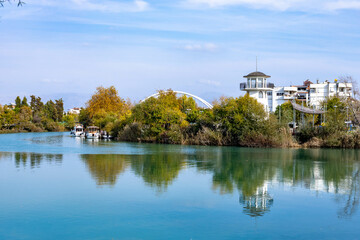 Panorama of the Manavgat River with turquoise water in the city center. Lighthouse on the river bank.