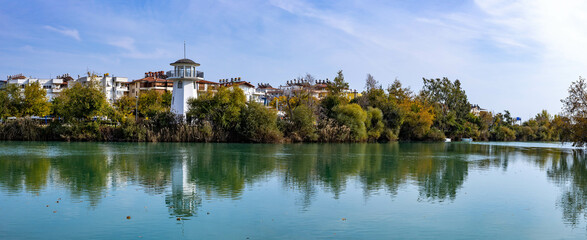 Fototapeta premium Panorama of the Manavgat River embankment in the city center with a lighthouse on the river bank.
