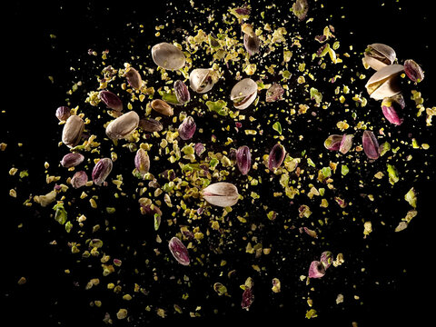 Explosion of raw peeled, crushed and pistachio with shells on black background, studio shot