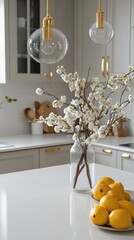 White blossoms in a glass vase, a bowl of lemons, and brass pendant lights illuminate a modern kitchen with white cabinets and quartz countertops. The scene evokes feelings of springtime freshness