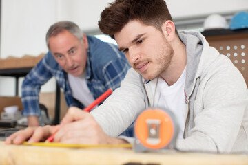 bearded handsome cabinetmaker at the tabletop with pencil