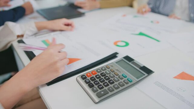 Accountant using a calculator for financial statement tax analysis investment planning office meeting. women Leadership in financial analysis, collaboration in business strategy saving reports