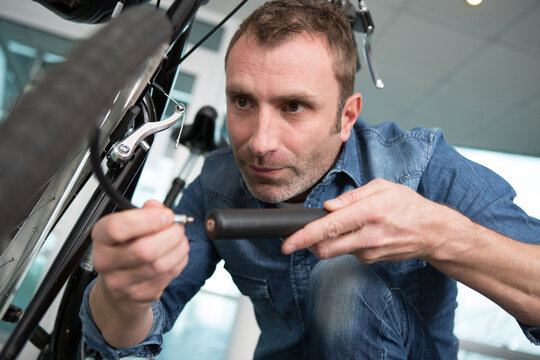 middle aged man inflates bicycle wheel using a pump