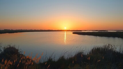 Obraz premium A serene sunset over a tranquil body of water, reflecting vibrant colors in the sky.