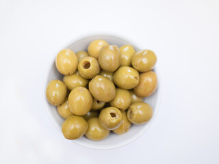 pitted green olives in bowl on white background