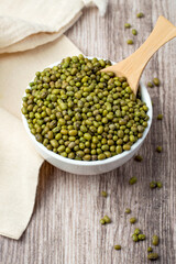 Mung beans in a bowl and spoon on a wooden background..
