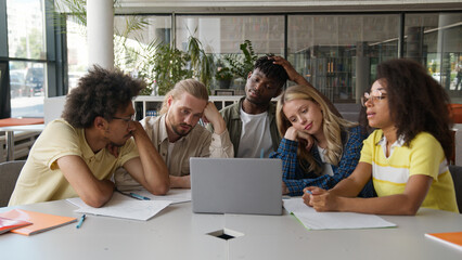 Tired exhausted stressed boring diversity five multiethnic students Caucasian women girls female African American men male guys together studying at university laptop online homework teamwork problem
