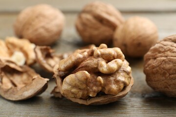 Fresh walnuts with shells on wooden table, closeup