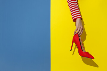 Woman showing red high-heeled shoe on color background, closeup and space for text. Stylish...