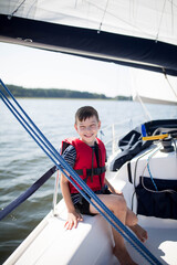 Młody chłopiec bezpiecznie żegluje z rodzicami w kamizelce ratunkowej © Katarzyna Krociel