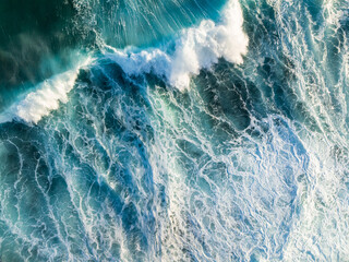 Ocean waves crash in Maniniholo Bay off north coast of Kauai, from an aerial perspective with winter surf and waves