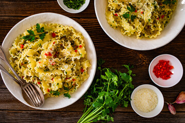 Pasta with garlic, parsley and pepperoncino on wooden table. Boiled mafaldine noodles. Spaghetti aglio olio e peperoncino on wooden background