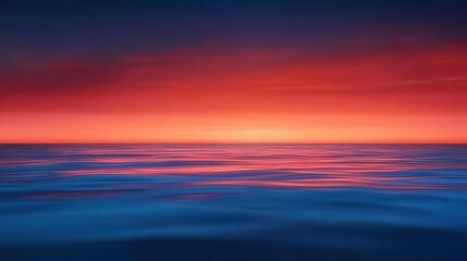 Fototapeta premium A stunning seascape featuring a vibrant sunset where the sky transitions from deep blue to fiery orange hues reflecting on the calm ocean surface, creating a serene and peaceful at