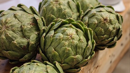 Obraz premium Fresh artichokes with green spiky leaves on rustic counter