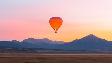 Fototapeta premium Hot air balloon flying over mountain valley at sunset. Orange balloon silhouette against purple and pink sky background. Scenic adventure landscape photography with copy space