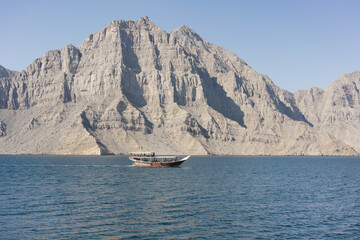 Dhau vor einer Felswand im Musandam Fjord bei Khasab, Oman