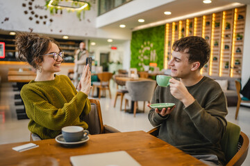 girlfriend use mobile phone to take a photo of her boyfriend at cafe