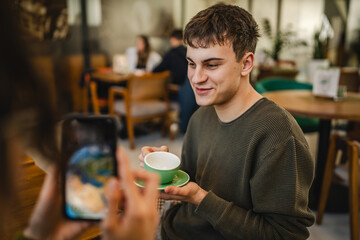 girlfriend use mobile phone to take a photo of her boyfriend at cafe