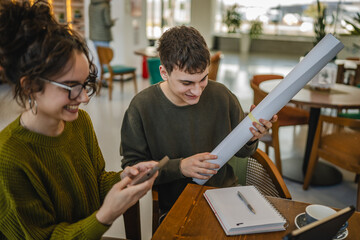 man prepare equipment for university while woman use cellphone at cafe