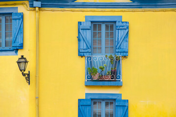 Yellow wall and blue window shutters exterior house in Portugal. Colorful buildings europe. Urban background. 