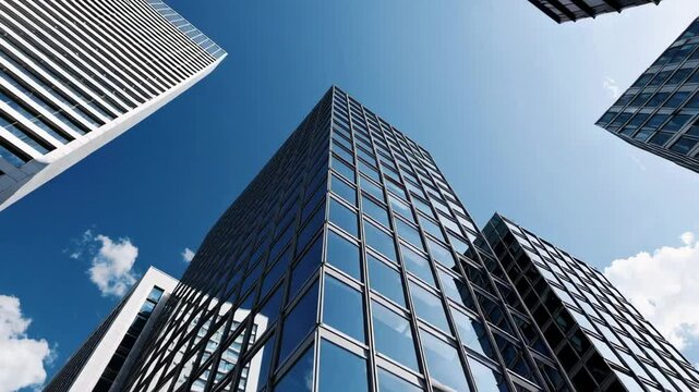 Glass skyscrapers reflecting blue sky and clouds create a powerful image of modern architecture and urban development, captured in a slow motion sequence