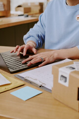 Individual working on laptop in organized office environment with various papers and stationary around workspace contributing to productive atmosphere without distraction