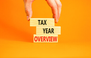 Tax year overview symbol. Concept words Tax year overview on beautiful wooden blocks. Beautiful orange background. Businessman hand. Business tax year overview concept. Copy space.