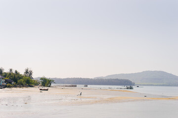 Peaceful Coastal Scene with Boat, Sandbank, and Hills in the Background.