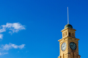 Historic Clock Tower Against a Clear Blue Sky with Sparse Clouds
