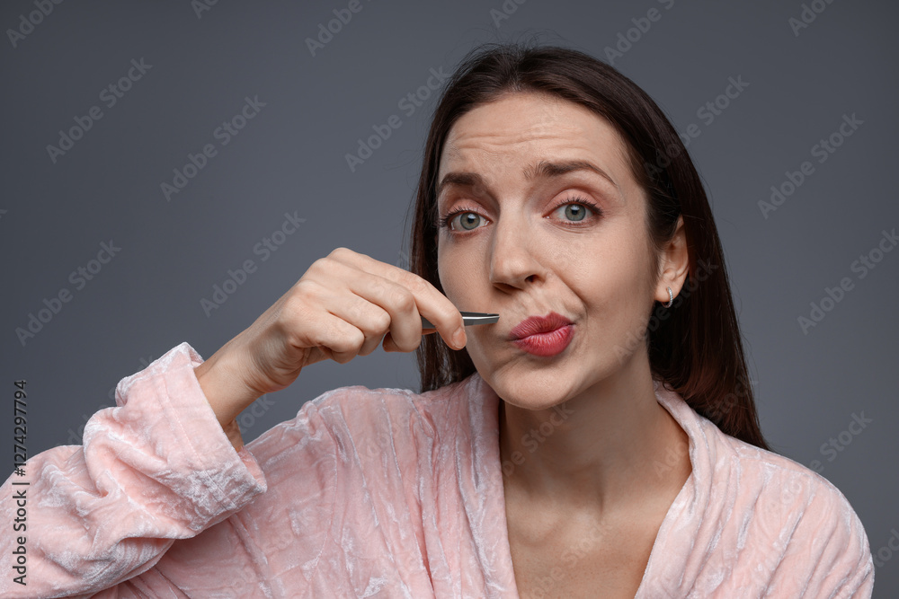 Canvas Prints Beautiful woman plucking her mustache with tweezers on grey background