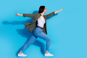 Young woman in a dynamic pose wearing casual outfit against a vibrant blue background