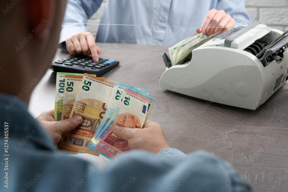 Poster Client counting money at table in currency exchange, closeup