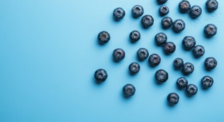 Fresh blueberries scattered on a light blue surface ready for snacking or baking desserts